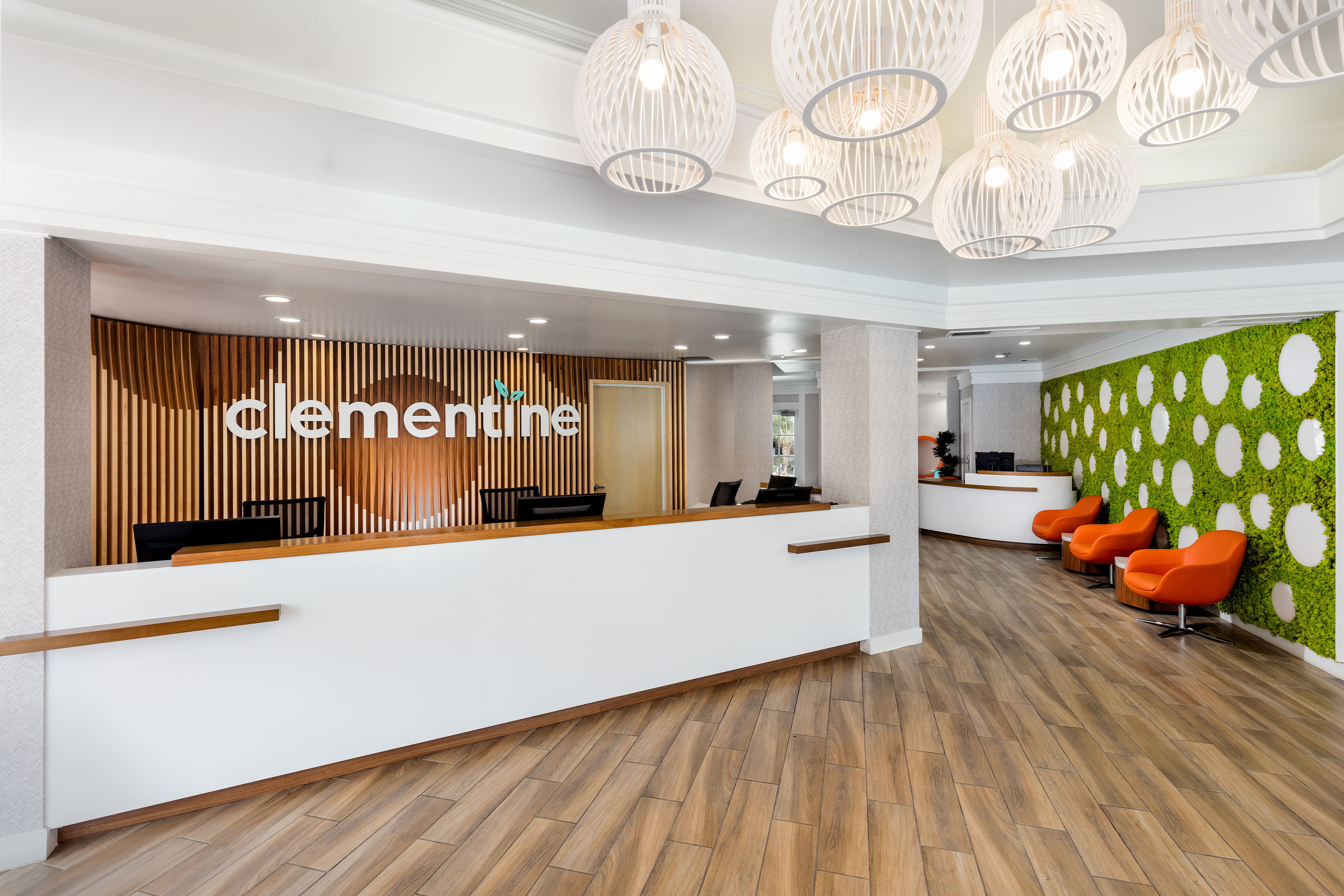 A modern hotel lobby with a reception desk, chairs, and stylish lighting fixtures.